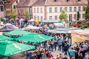 Große Menschenmengen unter großen Schirmen im Hintergrund Mehrfamilienhäuser