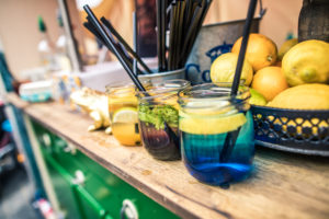 Bunte Cocktailgläser mit Strohhalmen und Zitrusfrüchten auf einer Ablage