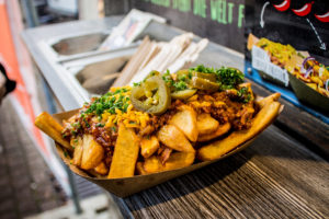 Frittierte Kartoffelscheiben mit Röstzwiebeln in einem Pappteller