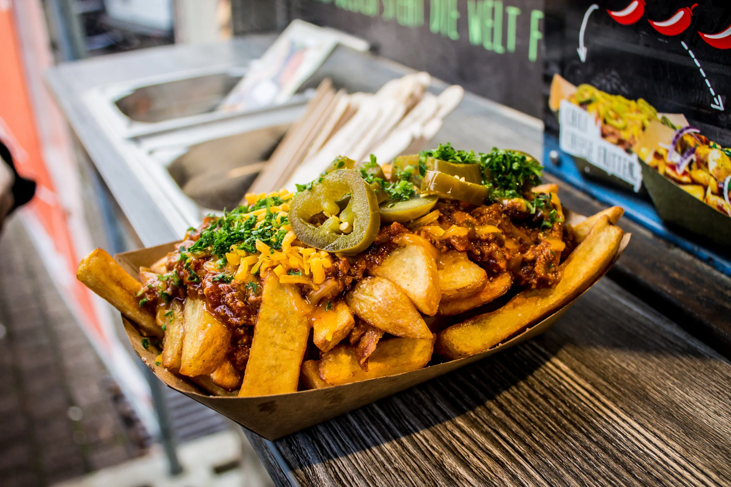 Frittierte Kartoffelscheiben mit Röstzwiebeln in einem Pappteller