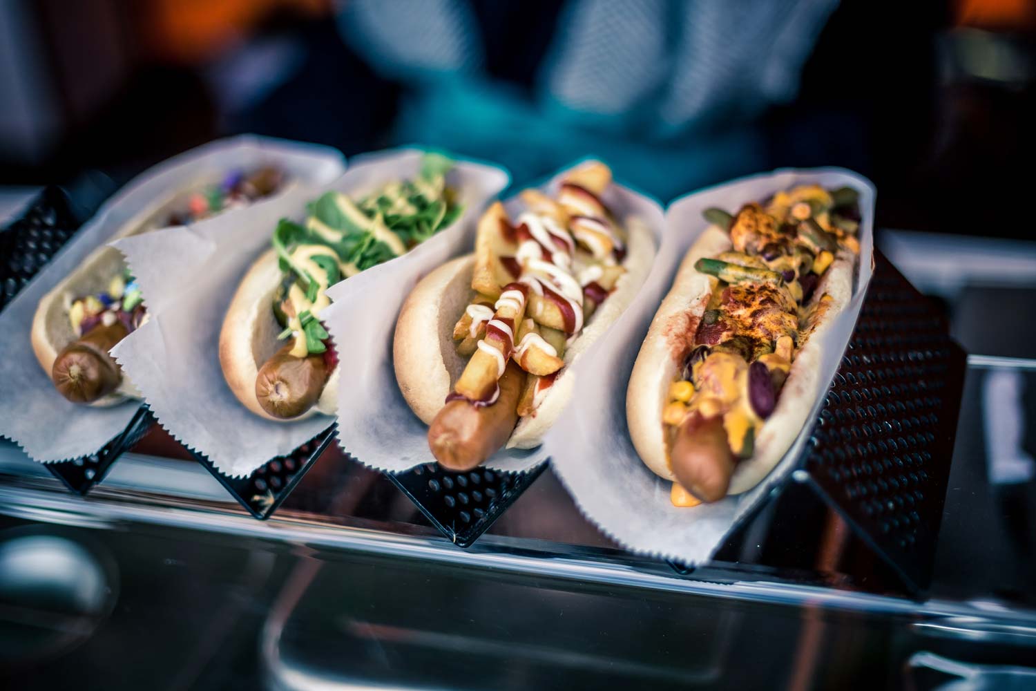 Vier verschiedene Hot Dog Varianten auf einem Metallständer präsentiert